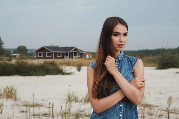 Maro cu păr femeie rurală în picioare pe nisip împotriva fermei casa — Fotografie, imagine de stoc