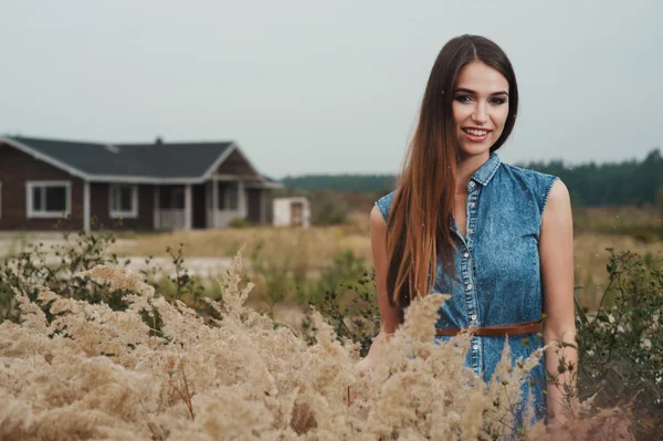 Lindo campo señora de pie en la hierba alta contra rancho casa — Foto de Stock