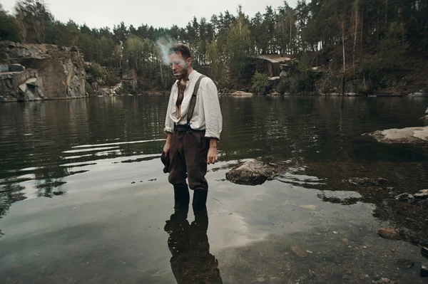 Neoholený zlatokop kouření v jezeře s skalnatá stráň — Stock fotografie