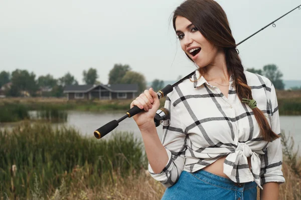 Dame de campagne debout contre l'étang sur le ranch avec tige de poisson — Photo