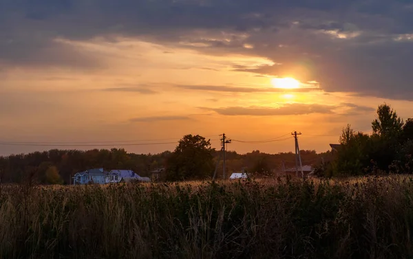 Evening in the village. Sunset over a field and houses in the background. Mouth of the Kama River, which flows into the Volga River, Republic of Tatarstan, Russia.