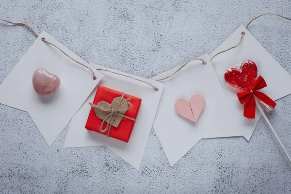 Flat lay romantic photography with gift box and paper origami heart on natural background. Romantic greeting card template.