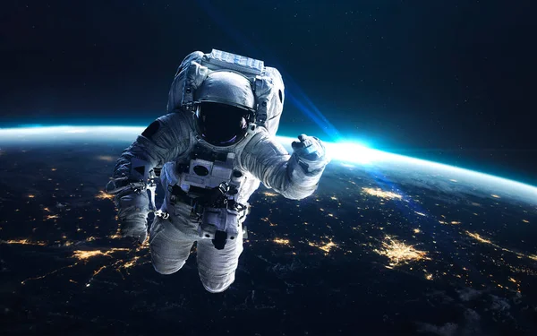 Астронавт на вихід у відкритий космос. На Землі вночі, світло міста з орбіти. Елементи цього зображення, надані НАСА. — стокове фото