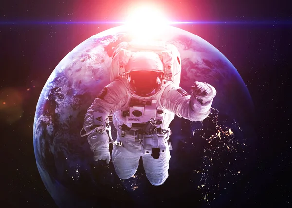 An astronaut floats above Earth. Stars provide the background. E — Foto de Stock