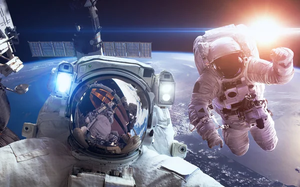 Международная космическая станция с астронавтами над планетой Земля. Элементы этого изображения предоставлены НАСА — стоковое фото
