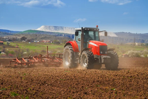 Nagelneuer roter Traktor pflügt das Land — Stockfoto