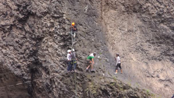 Groep van ongeïdentificeerde mensen die over de Tibetaanse brug in Banos de Agua Santa oversteekt — Stockvideo