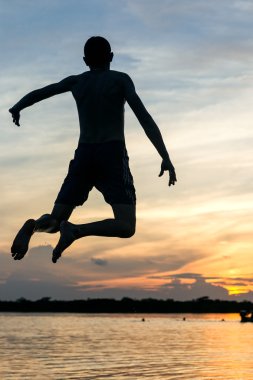 Gün batımında göle dalış adam siluet