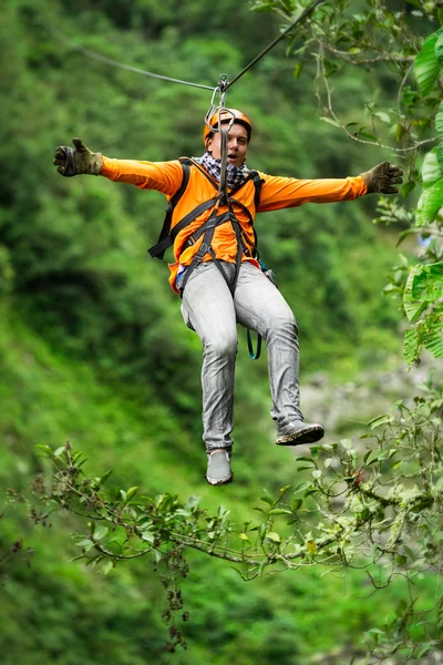 Orange klädda turist på Zip linje mot skogen — Stockfoto