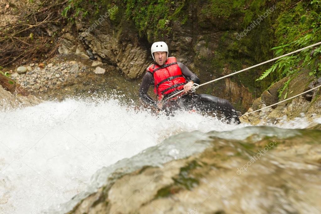 Brave Adult Man Rappelling A Waterfall