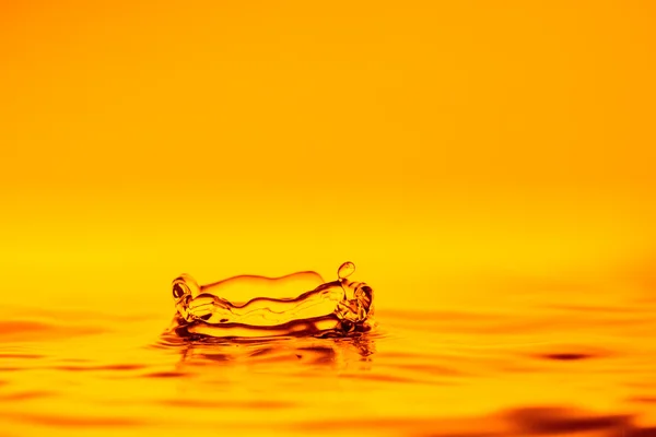 Gota de agua salpica en líquido amarillo —  Fotos de Stock