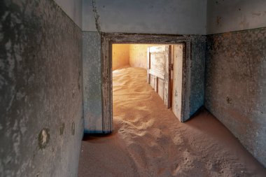 Namibi 'nin Kolmanskop kasabasında terk edilmiş çöl kumlarıyla dolu bir ev.