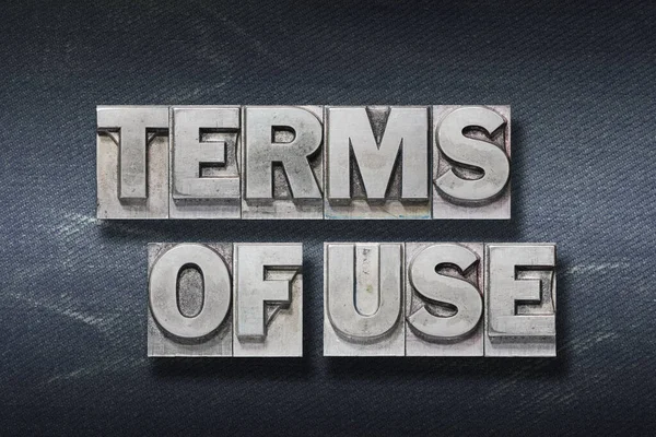 terms of use phrase made from metallic letterpress on dark jeans background