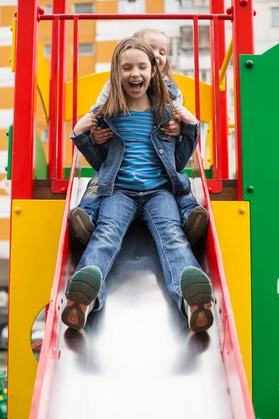 Meninas desliza para baixo da colina no parque infantil — Fotografia de Stock