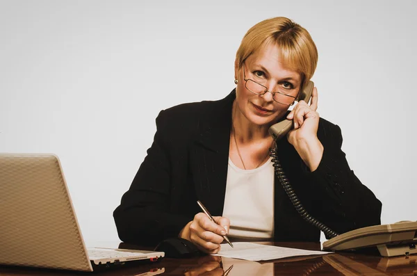 Зрелая деловая женщина звонит по телефону на рабочем месте — стоковое фото