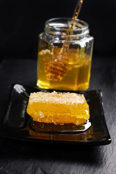 Honeycomb on plate and honey in glass jar with spoon — Stock Photo, Image