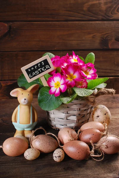 Easter eggs with clay rabbit and primula flowers in pot — Stock Photo, Image