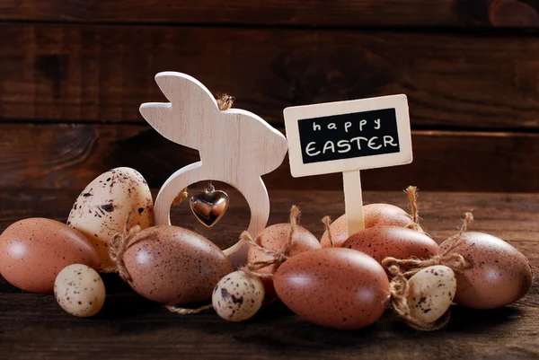 Easter eggs and wooden decorations with greetings on chalkboard — Stock Photo, Image