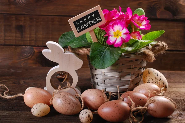 Пасхальные яйца с деревянным кроликом и цветками примулы в горшке — стоковое фото