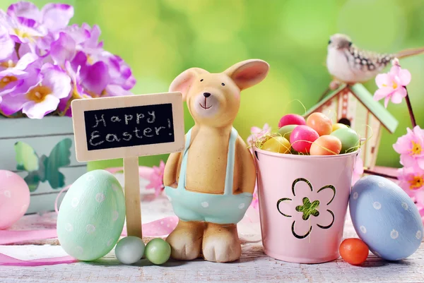 Tarjeta de Pascua con conejo de arcilla y decoraciones en el fondo de primavera —  Fotos de Stock