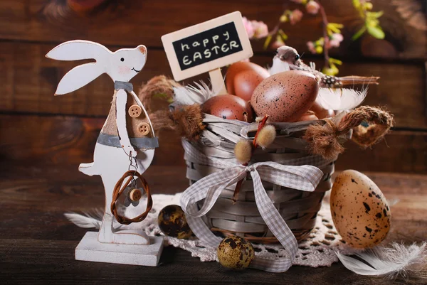 Easter eggs in old basket and funny rabbit decoration — Stock Photo, Image