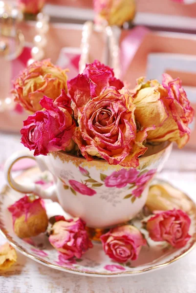 Beautiful dried roses in porcelain teacup — Stock Photo, Image