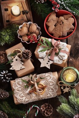 Daire, DIY ile yatıyordu, dantelli, ipli ve ahşap masa üzerindeki kırsal tarzda dekorlarla yaratıcı bir şekilde paketlenmiş Noel hediyeleri