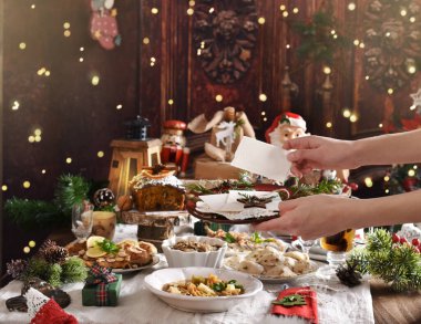 Noel arifesi ekmeğini geleneksel yemeklerle birlikte elinde tutan kadının elleri.