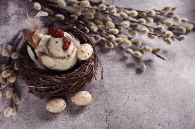 Yuvasında gri beton duvar arka planında duran tavukçu heykelciği olan Paskalya kartı.