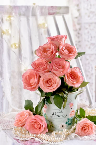 bunch of pink roses in bucket standing on the chair and pearls and shabby chic style interior