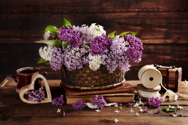 Hasır sepetin içindeki leylak demeti ahşap masanın üzerinde kırsal tarzda. 