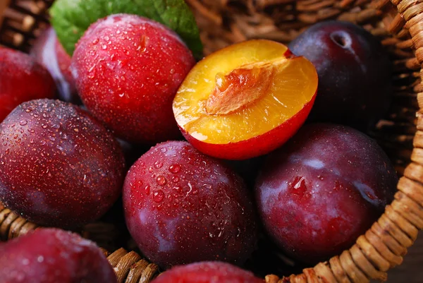 Fresh plums falling out of a basket — Stock Photo, Image
