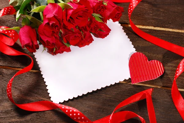 Bunch of roses and blank card on wooden background — Stock Photo, Image