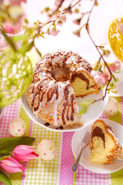 Ringkuchen mit Zuckerguss und Schokoglasur auf Ostertisch Stockbild