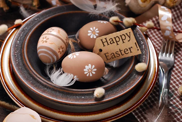 Easter eggs and paper tag with greetings in plate on rustic tabl — Stock Photo, Image