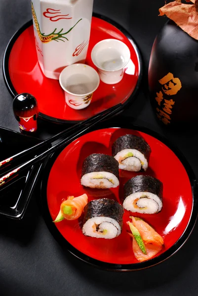 Суші макі на червоній тарілці і саке — стокове фото