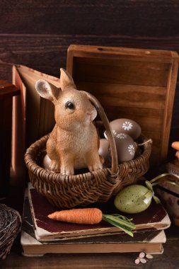 Hasır sepette yumurtalarla oturan sevimli tavşan heykelciğiyle taşra tarzı Paskalya dekorasyonu.