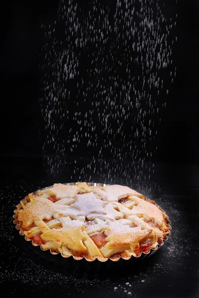 Tarta de manzana y azúcar en polvo que cae sobre la mesa negra — Foto de Stock