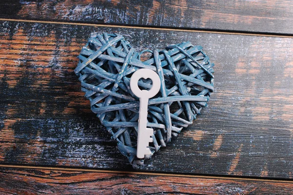 Blue wicker heart and a key on shabby wooden background — Stock Photo, Image