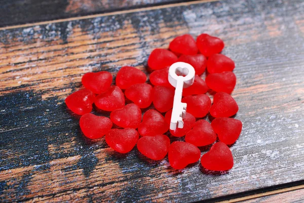 Rood hart gemaakt van snoepjes en een sleutel op shabby achtergrond — Stockfoto