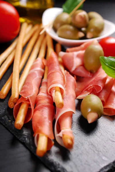 Grissini-Stockbrot mit Schinken auf schwarzem Brett — Stockfoto