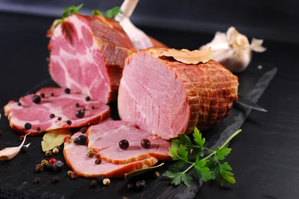 Stücke hausgemachten geräucherten Schweinefleisch auf schwarzem Hintergrund — Stockfoto