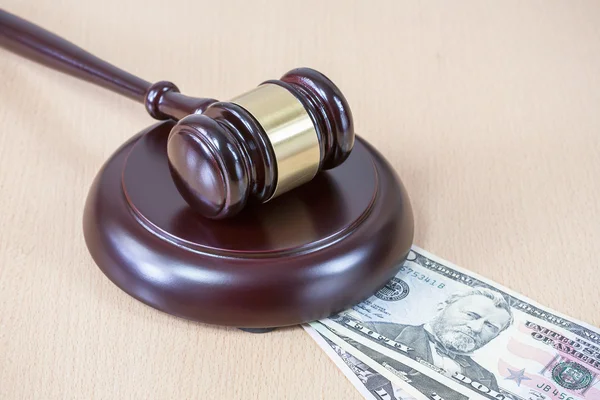 A wooden gavel on wooden table, on brown background, dollars — Stock Photo, Image