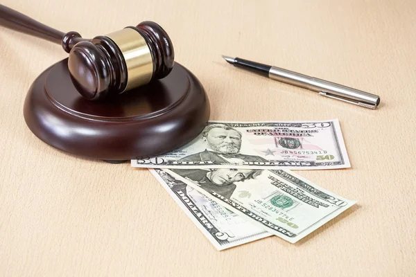 A wooden gavel on wooden table, on brown background, dollars — Stock Photo, Image