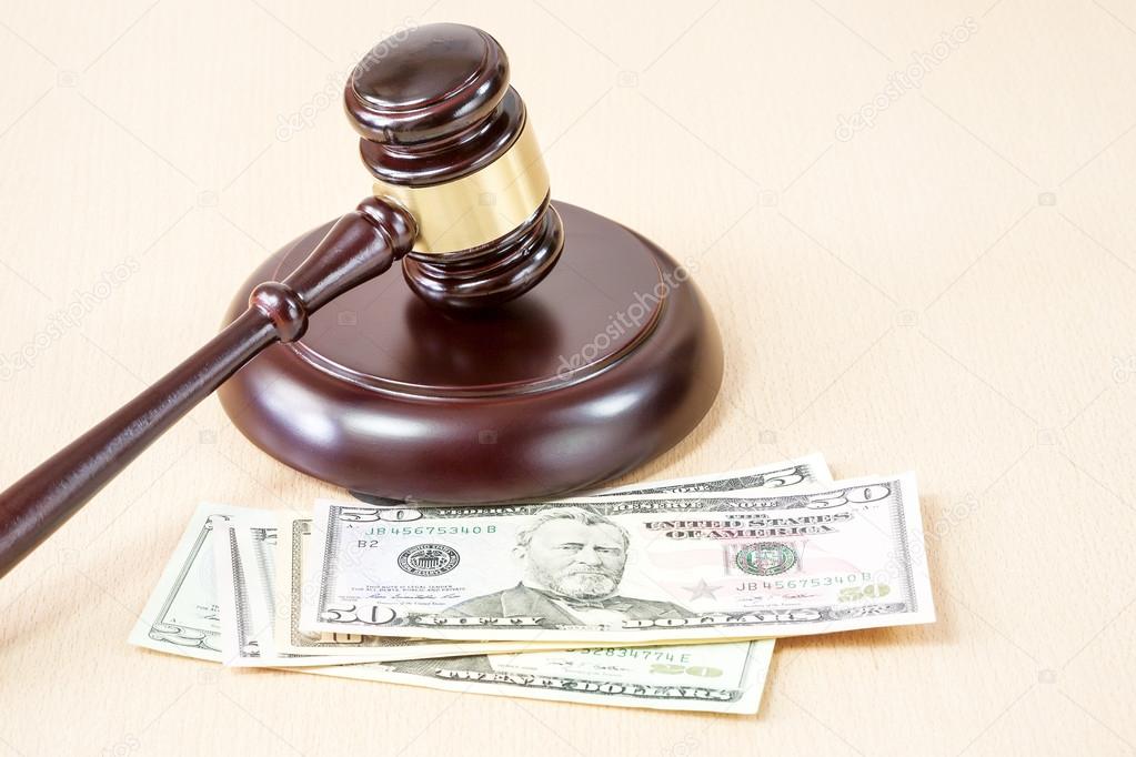 A wooden gavel on wooden table, on brown background, dollars