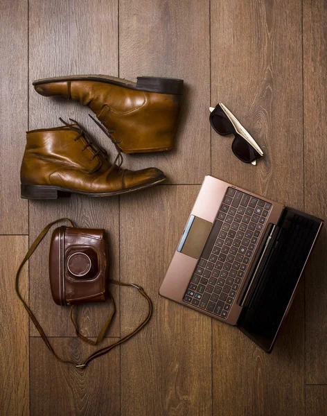 Zapatos marrones, cinturón, bolsa y cámara de película con ordenador portátil Fotos de stock