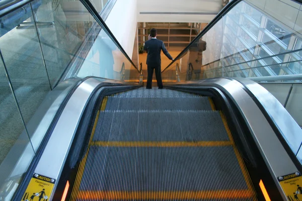 Hombre montando por una escalera mecánica —  Fotos de Stock