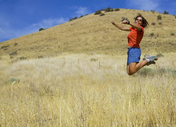 Flickan hoppar högt i fältet — Stockfoto