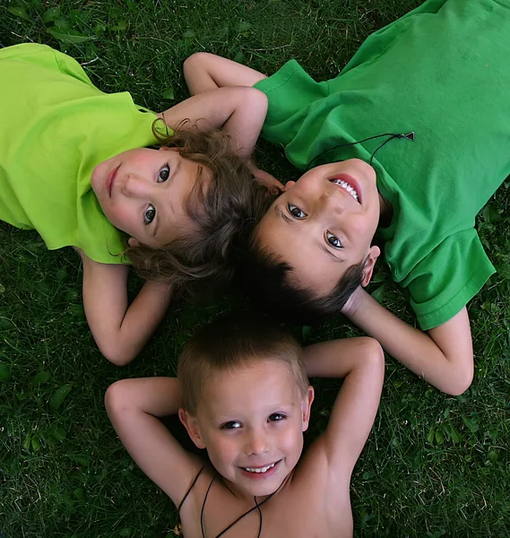 Drei Kinder liegen im Gras — Stockfoto