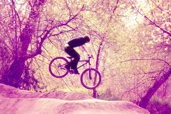 Biker andar de bicicleta sobre um salto — Fotografia de Stock